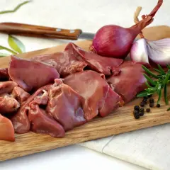 Surowa wątróbka na desce z cebulą, rozmarynem i pieprzem. Czy wątróbka to mięso? Tak, to organ mięśniowy.