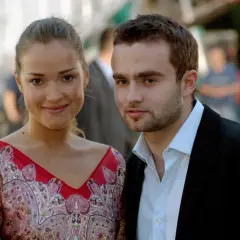 Alicja Bachleda-Curuś z partnerem, uśmiechnięta aktorka w kolorowej sukience i elegancki mężczyzna w garniturze.