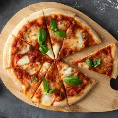 Ania gotuje ciasto na pizzę. Na drewnianej desce leży pyszna pizza margherita z bazylią, pokrojona na kawałki.