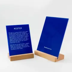 Deux panneaux en **lettre plexiglas** bleus sur des supports en bois. L'un décrit le processus de fabrication de Mister, l'autre affiche le hashtag #madebymister.