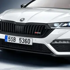 Biała Skoda Octavia 4 z czarnym grillem i czerwonym znaczkiem VRS. Zbliżenie na przednią część samochodu.