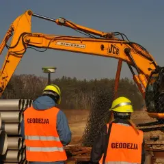 Geodeci w kamizelkach obserwują pracę koparki. Zastanawiasz się, ile kosztuje wynajem koparki?
