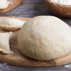Świeże ciasto na pierogi i kilka uformowanych pierożków. Zastanawiasz się, czy ciasto na pierogi można zrobić dzień wcześniej? Tak, można!