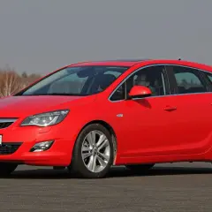 Czerwona Opel Astra na drodze. Kierowca za kierownicą. Jaki akumulator do tego modelu?