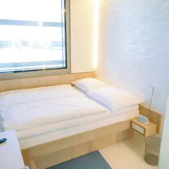 Nowoczesny pokój hotelowy z łóżkiem, oknem i pilotem.