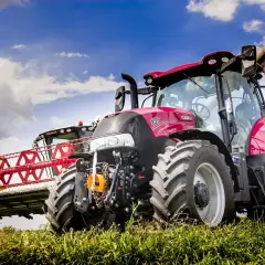 Czerwony traktor Case IH z hederem żniwnym i żółtą przyczepą. Warto wiedzieć, jak wymienić olej w takim sprzęcie, by służył latami.