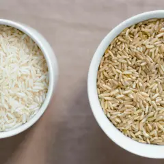 Zwei Schalen Reis: eine mit hellem Basmati oder Jasmin Reis, die andere mit braunem Reis.