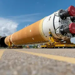 Ogromny człon rakiety SLS na wózku transportowym, gotowy do startu.