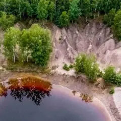 Widok z lotu ptaka na krajobraz przypominający łuk mużakowa z kosmosu, z wodą i drzewami.
