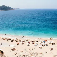 Piękna pogoda w Antalyi! Słoneczny dzień na plaży z turkusową wodą, ludźmi kąpiącymi się i odpoczywającymi pod parasolami.