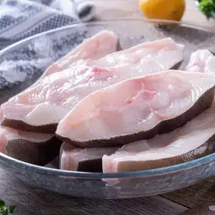 Świeże kawałki halibuta ryby w szklanej misce, gotowe do przygotowania.