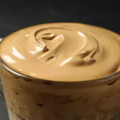 Cremiger Dalgona Kaffee in einem Glas, die aufgeschlagene Schaumkrone wirbelt wie ein Kunstwerk.