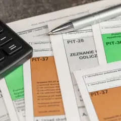Kalkulator i długopis leżą na dokumentach PIT-28, PIT-36 i PIT-37. Czas na rozliczenie podatku!