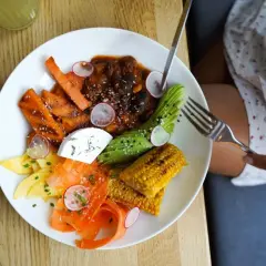 Assiette colorée avec carottes, avocat, maïs, fromage frais et viande en sauce. Une délicieuse alternative au riz pour un repas sain et savoureux.
