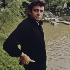 Johnny Cash, w czerni, stoi nad wodą. W jego oczach widać ból, jakby przeżywał coś trudnego, jak w piosence "Hurt".