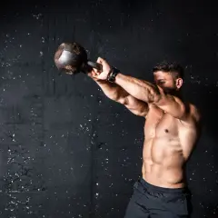 Mężczyzna ćwiczy z kettlebell. Intensywny trening, który pokazuje, co to znaczy wysiłek anaerobowy.