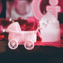 Różowy wózek dla lalek na przyjęciu gender reveal. Czy to będzie dziewczynka?