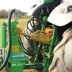 Grüner Traktor mit angehängtem Pflug. Ein gelber Walterscheid Oberlenker mit Hydraulikzylinder ist sichtbar.