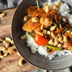 En skål med ris toppad med kyckling, grönsaker och krispiga kyckling cashew.