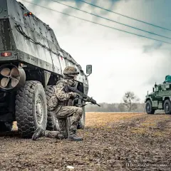 Żołnierz 18 Brygady Zmotoryzowanej klęczy przy transporterze opancerzonym, gotowy do akcji.