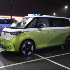 Zielony i srebrny VW ID. Buzz, jeden z niebieskimi światłami, parkuje nocą. Zasięg tych elektryków jest imponujący.