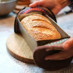 Świeżo upieczony chleb z sezamem w metalowej formie, gotowy do wyjęcia z nagrzanego piekarnika.