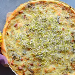 Pyszna tarta cebulowa z boczkiem, udekorowana kiełkami. Idealna na obiad lub kolację.