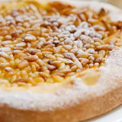 Deliciosa tarta de piñones, cubierta con azúcar glas, lista para disfrutar.