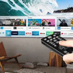 Smart TV z pilotem w dłoni, pokazujący aplikacje streamingowe. Czy smart TV potrzebuje anteny? Nie, jeśli korzystasz z internetu.