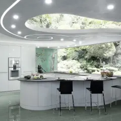 Cucina moderna con isola curva, pensili bianchi lucidi e un suggestivo controsoffitto a onda con illuminazione integrata. Pareti con carta da parati orientale e vista su un giardino lussureggiante.