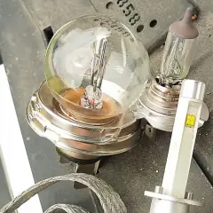 Stare żarówki słabo świecą w domu, obok nowoczesna lampa LED.