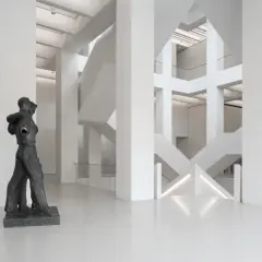 Rzeźba w nowoczesnym muzeum z betonową architekturą i schodami.