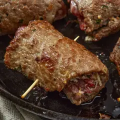 Involtini di carne succulenti, cotti in padella, con ripieno visibile e stuzzicadenti.