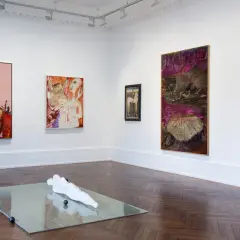 Artistic display at Michael Werner Gallery featuring abstract paintings and a sculpture on a mirrored surface.