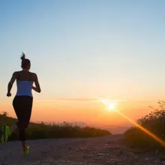 Läuferin genießt den Sonnenaufgang. Die beste Zeit zum Trainieren ist oft früh am Morgen, wenn die Natur erwacht.