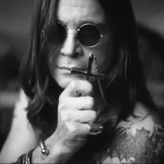 Ozzy Osbourne, ikona zespołu Black Sabbath, w okularach i z krzyżem w dłoni.