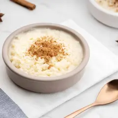 Un tazón de arroz con leche cremoso, espolvoreado con canela. ¿Quién inventó el arroz con leche? Un misterio delicioso.