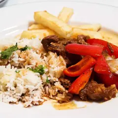 En tallrik med lomo saltado: ris, strimlat nötkött, rödlök, röd paprika och pommes frites.