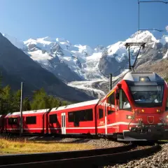 Rött tåg i alpint landskap med snöklädda berg. En resa genom norra Italien med fantastisk utsikt.
