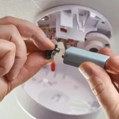 Hände wechseln Batterie eines Rauchmelders. Wichtig für die Versicherung und Sicherheit.