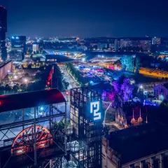 Nocny festiwal Tauron Nowa Muzyka w Katowicach. Widać sceny, tłumy ludzi i charakterystyczne budynki postindustrialne.