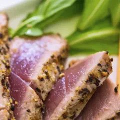 Saftiges Thunfischfilet, perfekt angebraten, mit einer würzigen Kruste, serviert mit frischem Grün und Honigmelone.