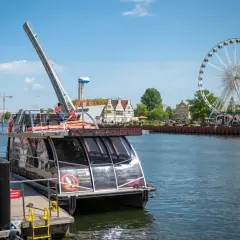 Statek wycieczkowy na Motławie w Gdańsku, w tle koło widokowe i zabytkowe kamieniczki.