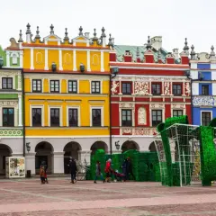 Kolorowe kamienice na Rynku w Zamościu, znane z unikatowych zdobień, tworzą malownicze tło dla świątecznej instalacji w kształcie prezentu.