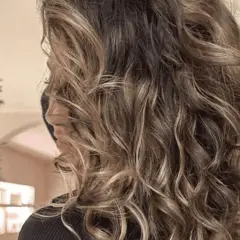 Melena castaña con mechas pelo rizado, luciendo ondas naturales y un brillo espectacular.
