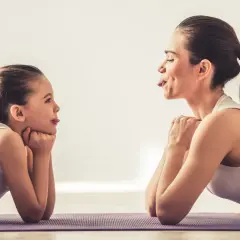 Mama i córka ćwiczą, wyciągając języki. Widać zaangażowanie mięśni wewnętrznych języka w zabawną zabawę.