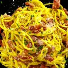 Spaghetti crémeux à la carbonara, garni de lard italien croustillant, de parmesan râpé et de ciboulette fraîche. Un délice !