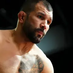 Rodolfo Vieira, en MMA-fighter med intensiv blick och tatueringar på bröstet, förbereder sig för strid.