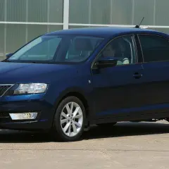 Ciemnoniebieska Skoda Rapid stoi na parkingu. Widoczny jest rozmiar opon, który idealnie pasuje do tego modelu.
