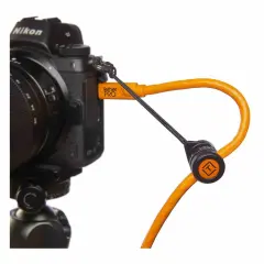En orange Tether Tools-kabel ansluten till en Nikon-kamera, redo för säker överföring av bilder.